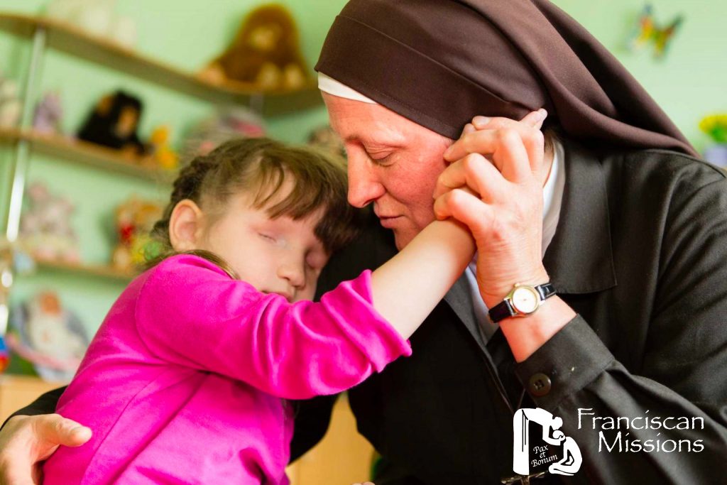 A Franciscan nun helps a child as part of the relief for Ukraine.