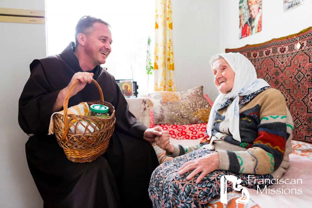 A Franciscan brother delivers food to an elderly woman as part of the relief for Ukraine.