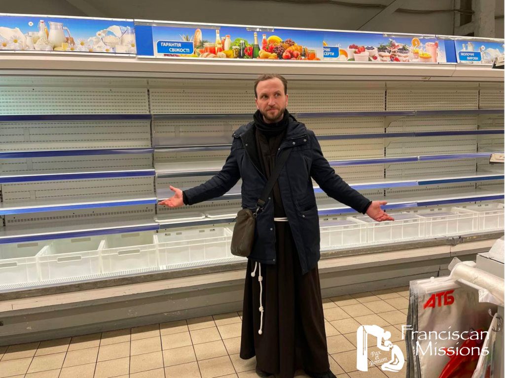 A Franciscan brother stands in front of empty shelves in a grocery store in Ukraine.
